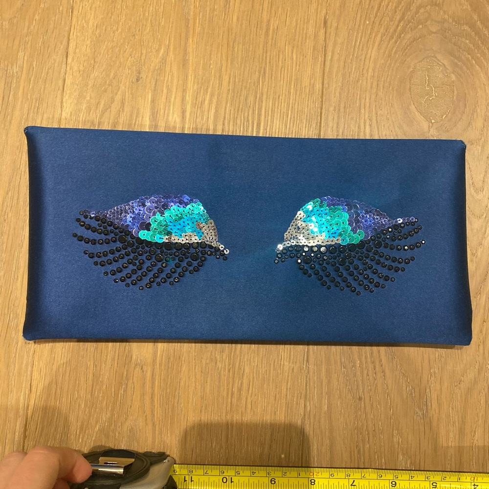 Satin navy clutch with sequin eyelid detail